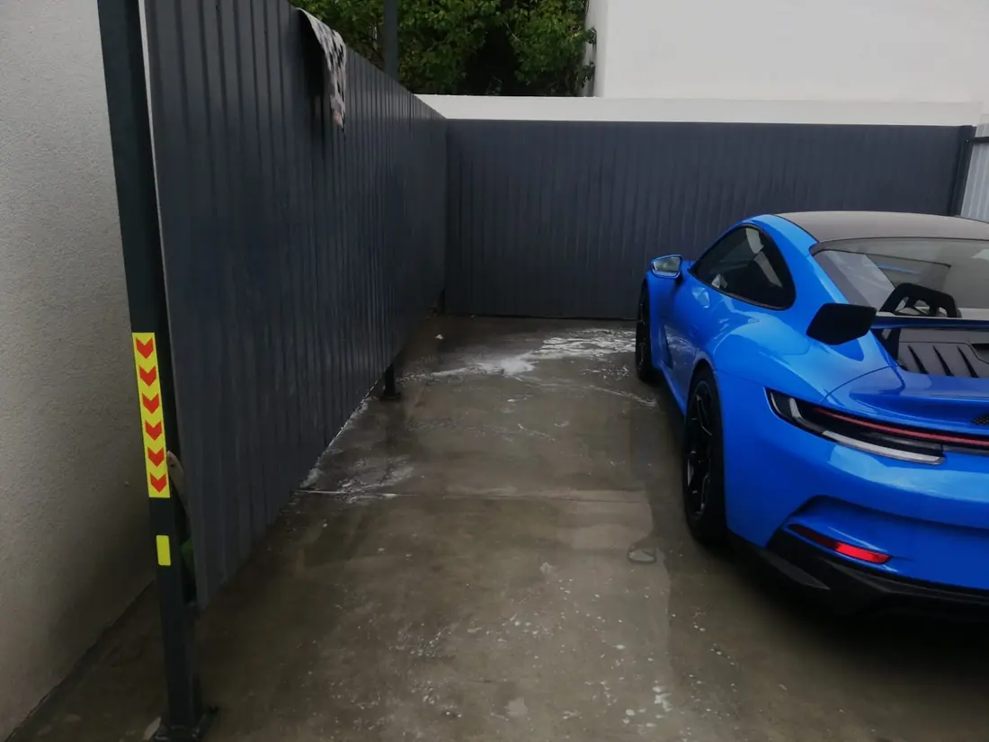 Porsche 911 albastru parcat lângă gardul antracit