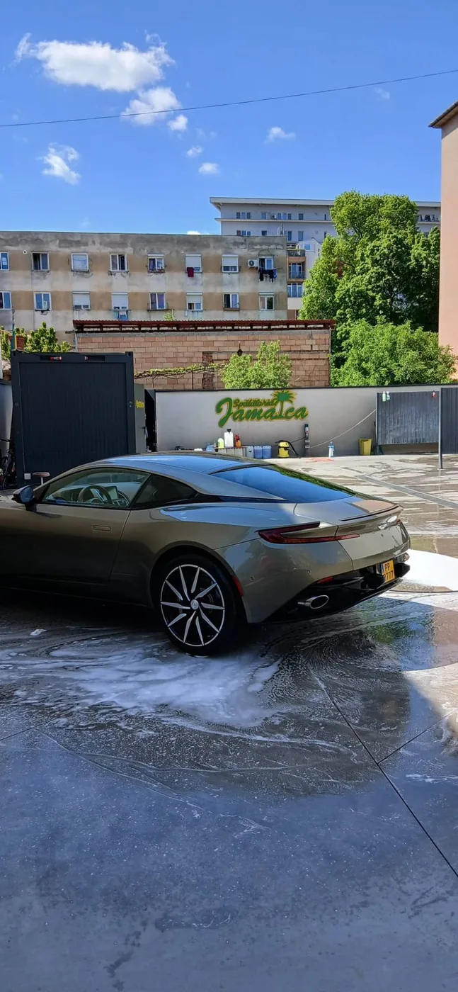 Aston Martin auriu-oliv pe betonul plin de spumă