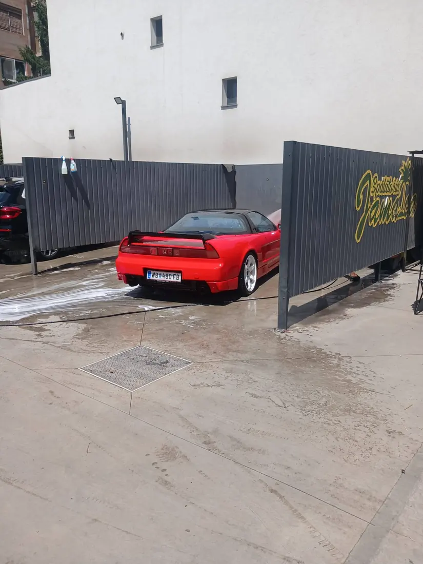 Honda NSX roșu clasic lângă panoul Spălătoriei Jamaica