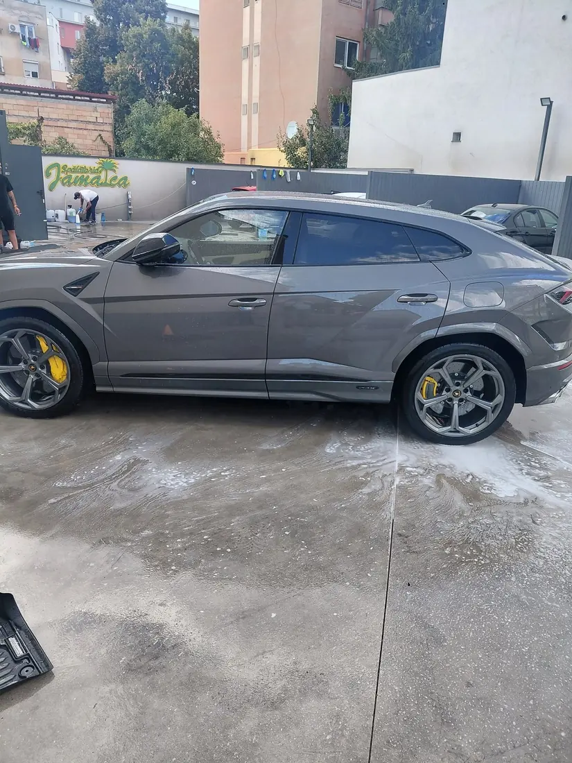Lamborghini Urus gri pe betonul ud al spălătoriei
