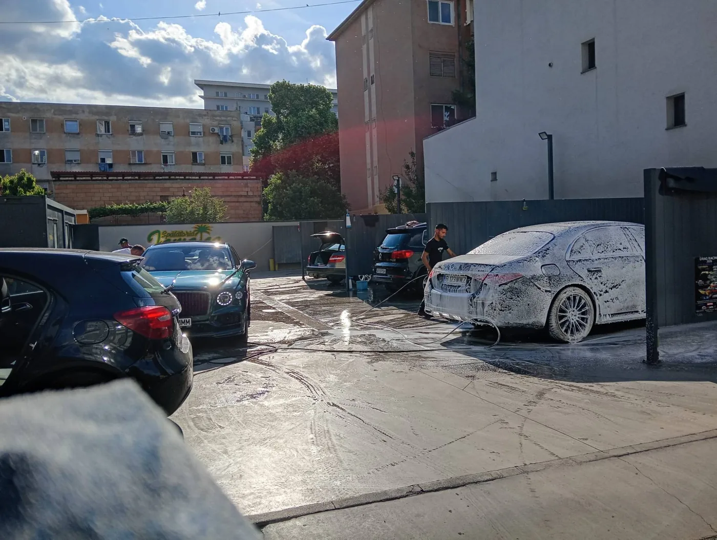 Mercedes acoperit de spumă activă, cu un Bentley și alte mașini la rând în curte